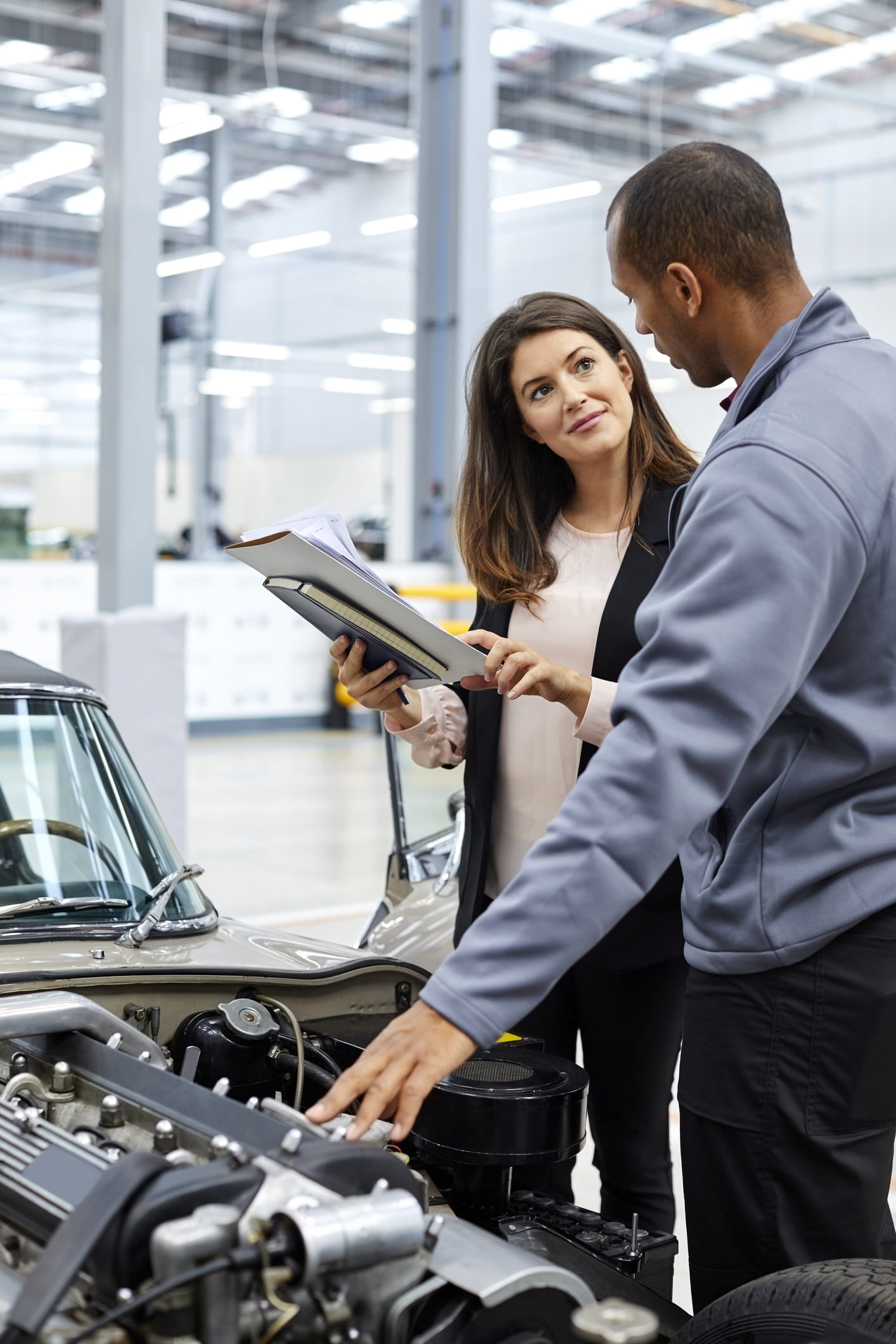 Ingeniero y supervisor discutiendo sobre el motor del coche