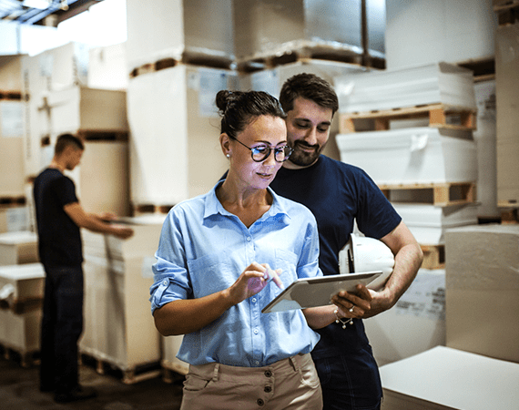 empleados hablan en almacen mirando una tablet